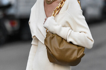 ženska v belem puloverju z rjavo torbico