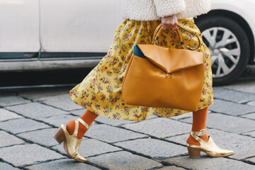 ženska v cvetličnem krilu z bež torbico