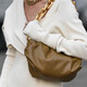 ženska z rjavo torbico v belem puloverju