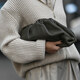 ženska drži črno torbico v sivem puloverju